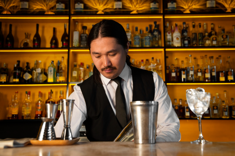 Focused bartender stirring a cocktail behind a well-lit bar, illustrating professional restaurant management tips in action during a shift.
