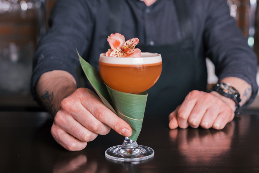 A bartender presents a visually appealing, high-margin signature drink with detailed garnishes.